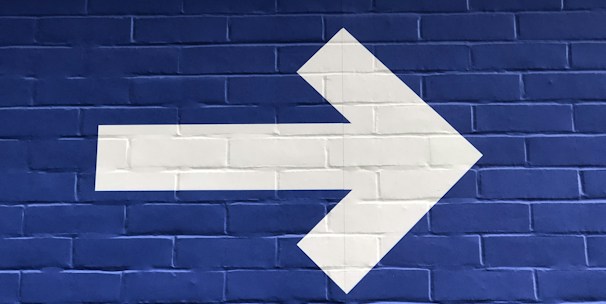 white arrow painted on brick wall