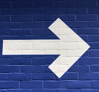 white arrow painted on brick wall