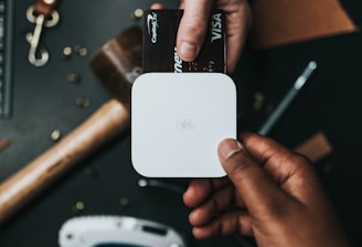 person holding Visa card and white device