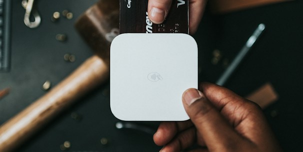 person holding Visa card and white device