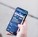 A hand holding a smartphone displaying a webpage titled 'Creating a Brand' with navigation options like Home, Discovery, Members, and Topics. The background is out of focus, providing a neutral setting.